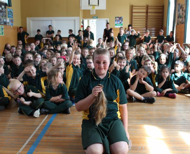 Nikita Bathgate in front of pupils at her Green Island school after shaving her hair to raise...