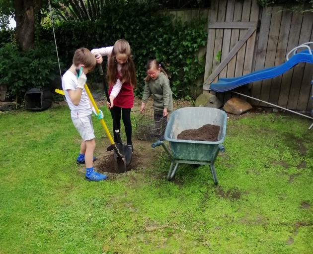 Siblings Oskar, Anika and Emily Doidge dig a hangi pit at their City Rise home. Photo: supplied