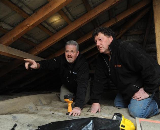 Craig Scoullar and Bruce Ritchie inspect old insulation in the ceiling space of a Halfway Bush...