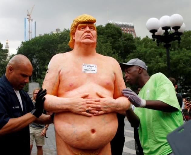 New York City Parks workers move a naked statue of Donald Trump that was left in Union Square...