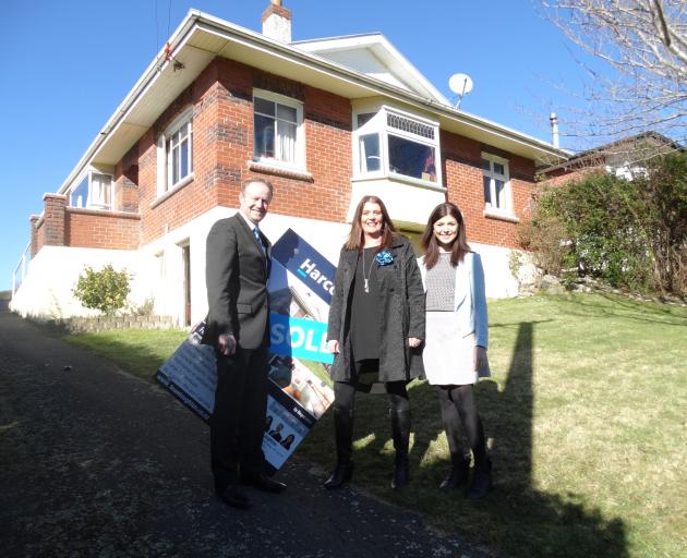 Harcourts Real Estate agents (from left) Mark, Penny and Emma Laughton stand in front of a house ...