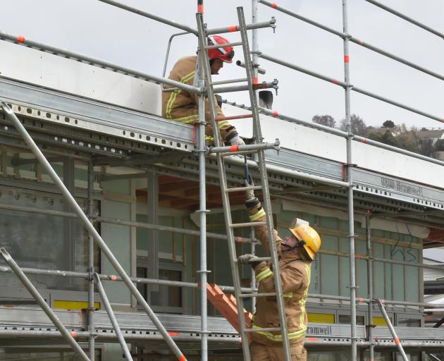 Roslyn firefighters secure loose roofing on a building site at Balmacewen Intermediate School ...