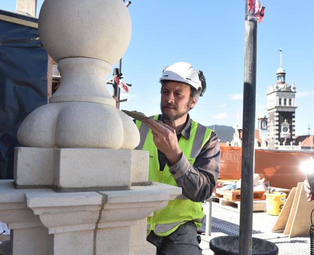 Stonemason Marcus Wainwright finishes pointing on a Oamaru stone finial on the roof of the former...