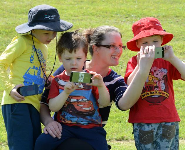 Playing an augmented reality smartphone game at Caversham Reserve yesterday are Eloise Sime and her sons (from left) Charlie (6), Quintin (4) and Lachlan (4). Photo by Linda Robertson.