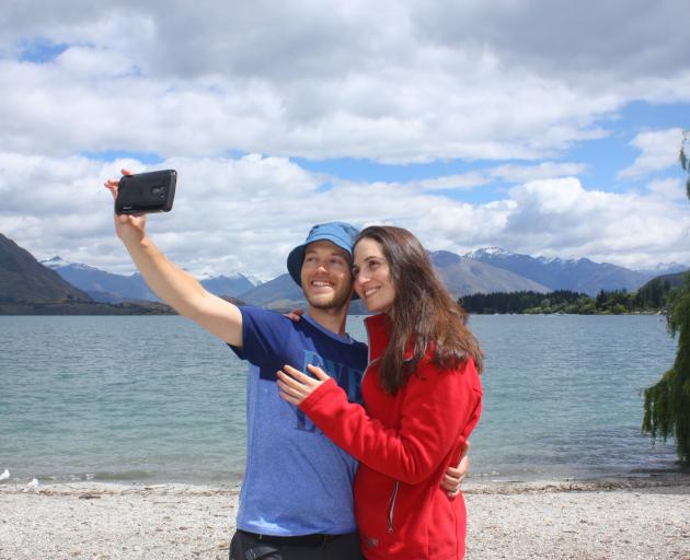Israeli tourists Noa David (left) and Elad Carmon take a photo with their cellphone in front of...