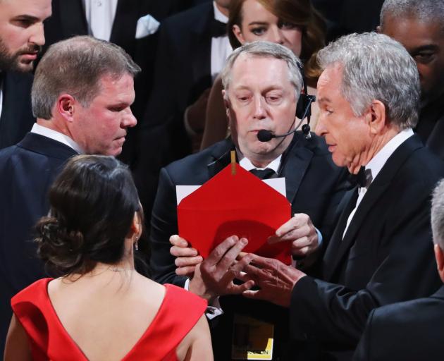 Brian Cullinan (left) and Martha Ruiz, of PricewaterhouseCoopers, look on as presenter Warren Beatty holds the card for the Best Picture Oscar awarded to Moonlight, after announcing by mistake that La La Land was the winner. Photo from Reuters.