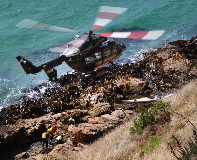 A helicopter hovers over rescuers attending to one of two kayakers trapped on rocks at Nugget...