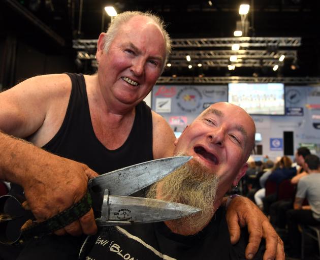 Former world champion blade shearer Peter Casserly proves to Adam Thomson, of Invercargill, that his blades are sharp enough to shave with. Photo by Stephen Jaquiery.