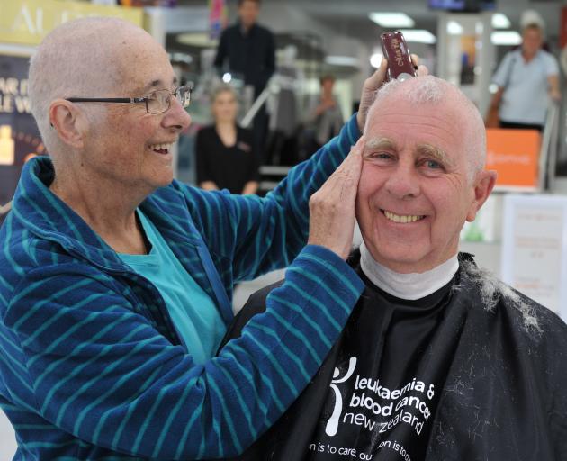 Kevin Bayne lets his wife Coleen shave his head as a show of support after she survived blood...
