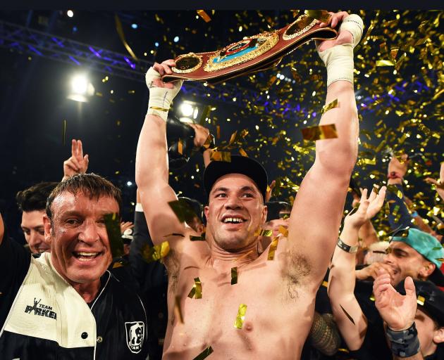 Joseph Parker holds the WBO heavyweight title belt aloft as his trainer, Kevin Barry (left),...
