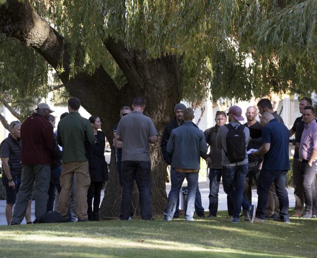 A group of plainclothes police and security wait outside reception at Millbrook Resort, Arrowtown...