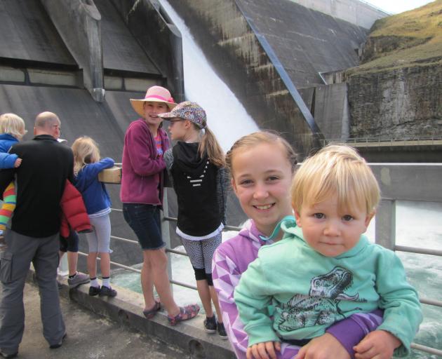 Libby Webb (10) holds her 1-year-old brother Boston as water flows down one of the Clyde Dam's spillways yesterday. The siblings and their parents were among about 5000 people who visited the dam and hydro-electric power station during an open day that ce