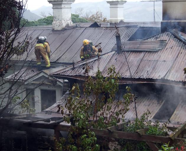 Firefighters check a Granville Tce house for hot spots at after a fire tore through the laundry and roof yesterday afternoon. Photo by Timothy Brown.