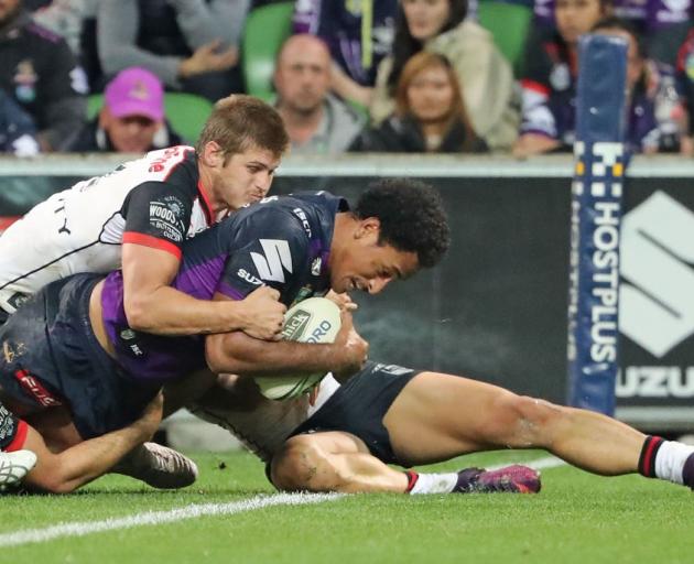 Felise Kaufisi scores for the Melbourne Storm as Blake Ayshford, of the Warriors, tries to stop...