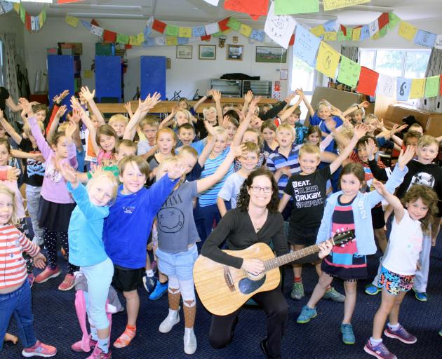 Cathy Irons (centre) leads a group of Hawea Flat School year 3 and 4 pupils through a song yesterday. Photo by Tim Miller.