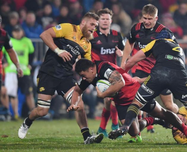 Crusaders hooker Codie Taylor is tackled in his team's match against the Hurricanes, two of the...