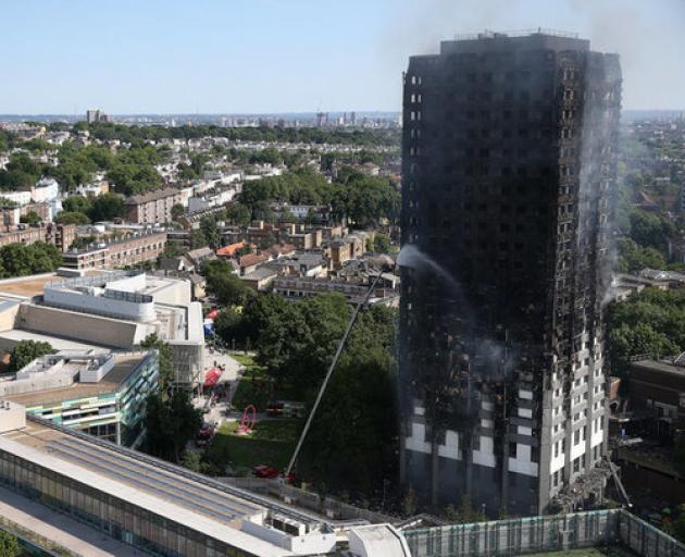 A firefighter directs a jet of water at a tower block severely damaged by a serious fire in West London. Photo: Reuters