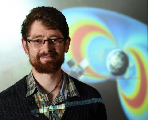 Aaron Hendry in front of an artist’s impression of Earth’s invisible radiation belts and one of...