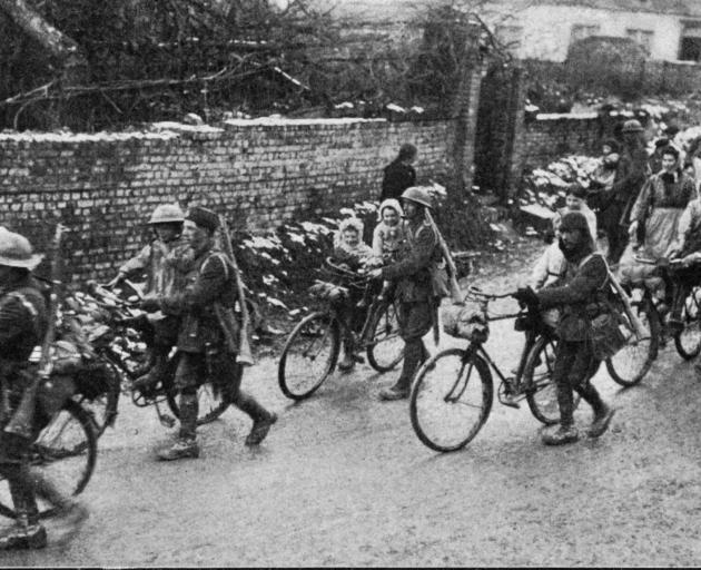 British soldiers from a cycle unit give French children a ride on their bicycles as they pass...