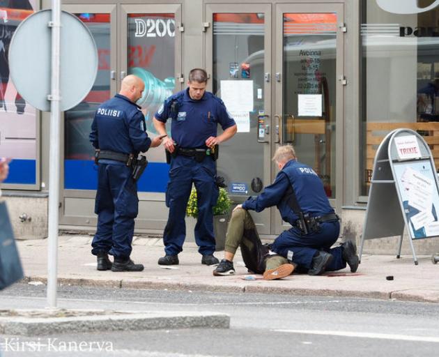 The suspect lies on the ground surrounded by police officers at the Market Square where several people were stabbed, in Turku, Finland. Photo: Reauters via Kirsi Kanerva