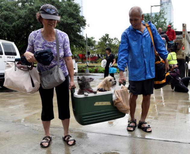 A couple of evacuees carry their dogs into the the George R. Brown Convention Center after Hurricane Harvey inundated the Texas Gulf coast with rain causing widespread flooding. Photo: Reuters