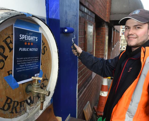 Williams Signs & Graphix signwriter Casey Munro paints near the Speight’s Brewery public water...