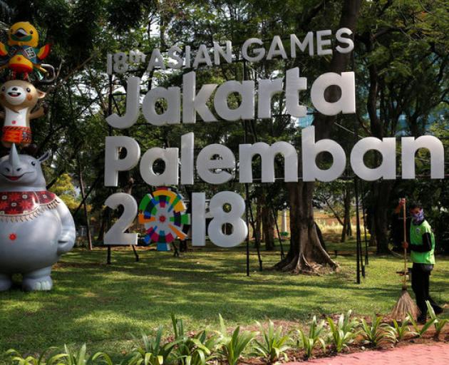 A worker cleans near a sign for the upcoming 2018 Asian Games, in Jakarta. Photo: Reuters