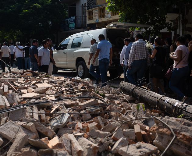 People walk by debris during a funeral ceremony held for a person that died in the earthquake in Juchitan, Mexico. Photo:Getty Images
