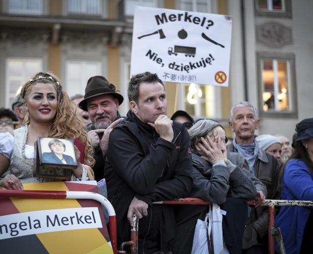 An Iranian Woman in traditional bavarian dress stands in front of protesters at Chancellor Angela...