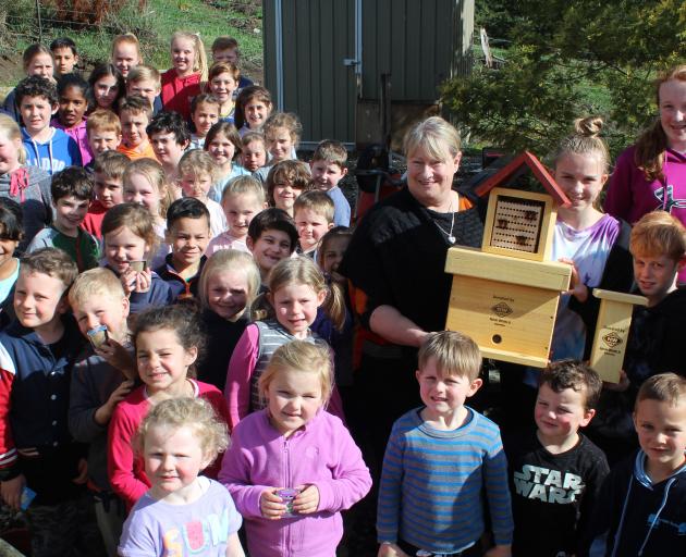 Warepa School principal Sue Adcock and pupils Keeley Puna (13), William Maze (10) and Lucy Clark (12, back right) are surrounded by the rest of the school as they hold on to the parts of a leafcutter bee house donated by New World owner Julie Broderick (r