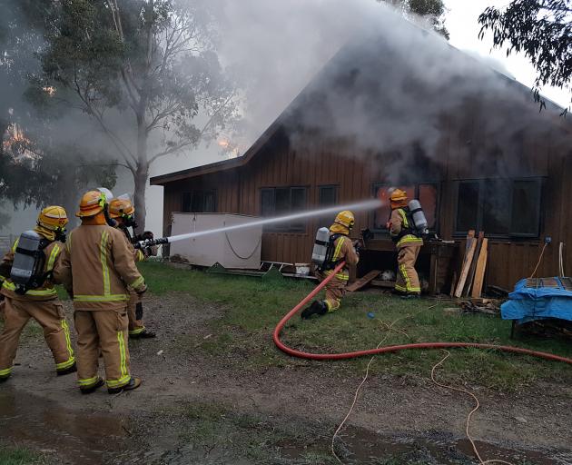Firefighters from the Lake Hawea and Wanaka volunteer fire brigades fight a garage fire in Camphill Rd on Tuesday night. The garage contained one vehicle and two quad bikes so the fire had to be extinguished externally. Photo: Brent Arthur