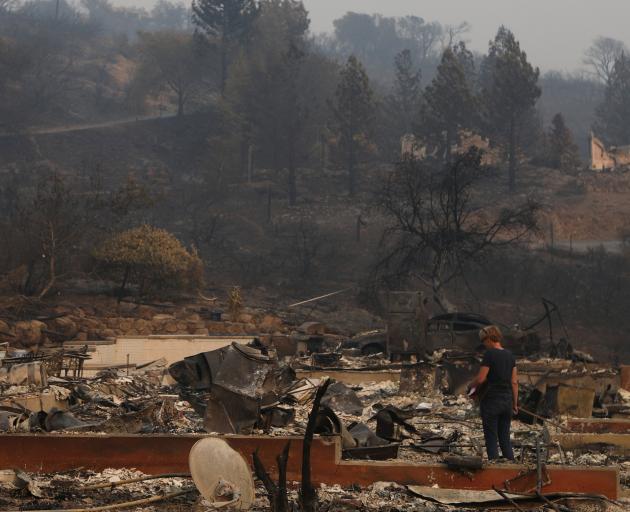 A woman surveys the remains of a home destroyed by wildfire in Napa. Photo: Reuters 
