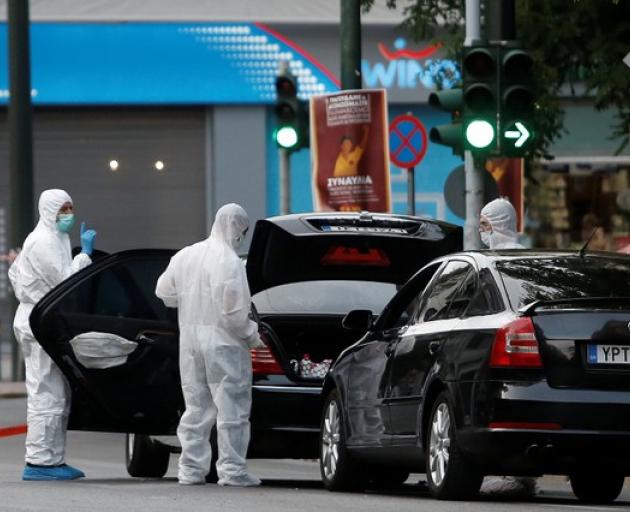 Forensics officers inspect the car of former Greek prime minister and former central bank chief Lucas Papademos following the detonation of an envelope injuring him and his driver, in Athens. Photo: Reuters