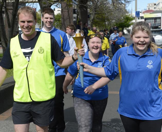 Senior Sergeant James Ure and Britney Kerr carry the Special Olympics Flame of Hope through central Dunedin yesterday as Special Olympians Keaton Bryant and Debbie Kennedy watch. Photo: Gerard O'Brien