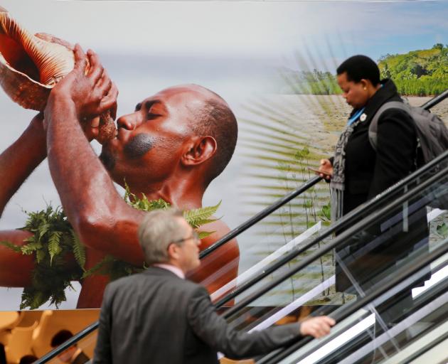 People pass by a placard at the COP23 UN Climate Change Conference in Bonn. Photo: Reuters