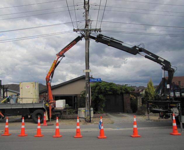 Cranes prop up a fallen power pole in Alexandra this afternoon. Photo: Pam Jones