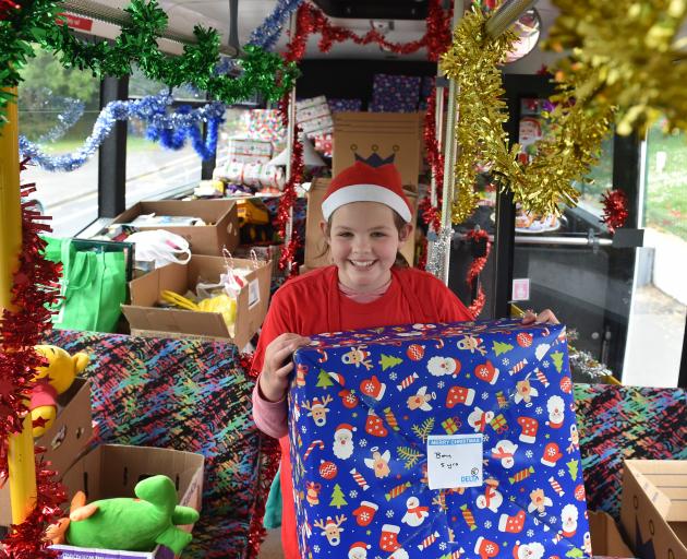 Wakari School pupil Isabelle Stanton brings a big gift on to the bus during a ‘‘Stock the Bus’’...