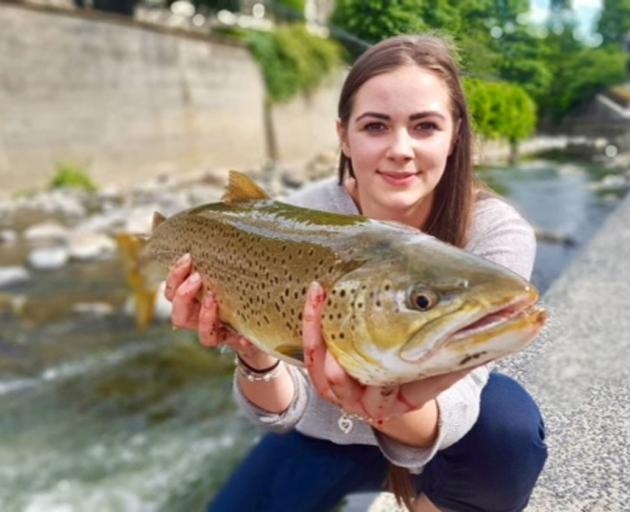 Adirah Coulter-Jeffrey shows off the large brown trout she caught in the Water of Leith at the University of Otago. Photo: Hannah Tobin