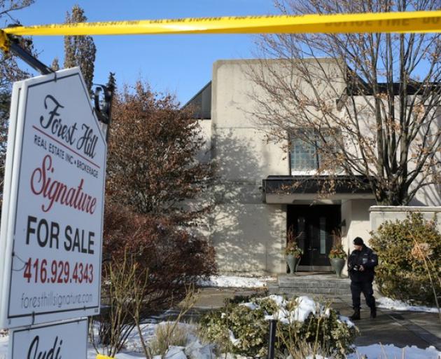 A police forensics photographer works outside the home of billionaire founder of Canadian pharmaceutical firm Apotex Inc. in Toronto. Photo: Reuters