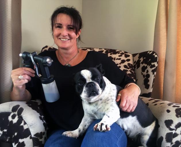 Primed Spray Tanning owner and operator Carmen Copland holds her spraygun and French bulldog Jiggy at her home in Kenmure, where she operates her spray tanning business. PHOTO: SHAWN MCAVINUE