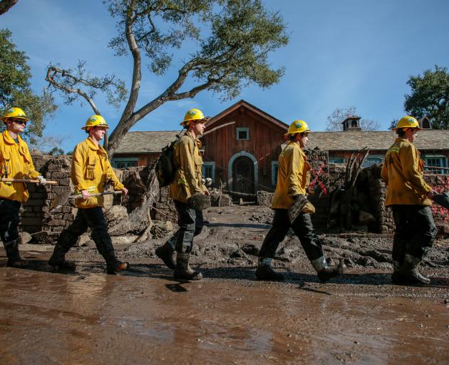 Rescue workers enter properties to look for missing persons after a mudslide in Montecito,...