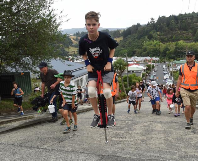 Harry Willis (11) bounces his way up the world’s steepest street on a pogo stick this morning....