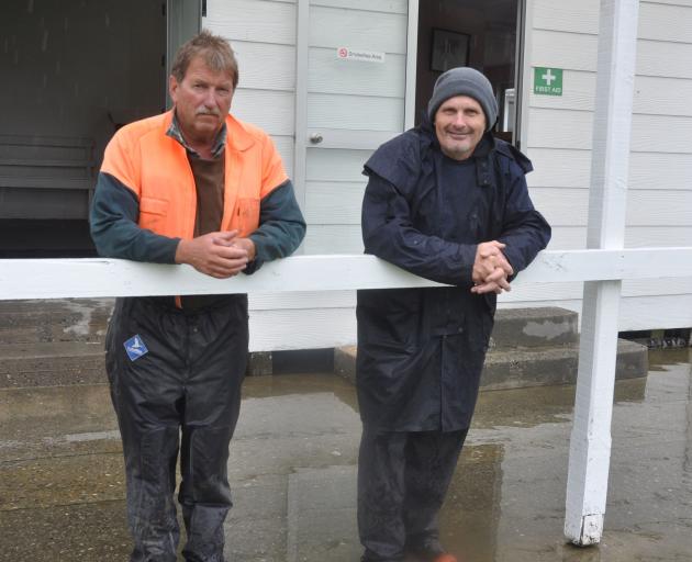 A dejected Kumara Racing Club acting president Patrick Meates, left, stands in water with the club's stipendiary steward Jeff McLaughlin at a sodden Kumara track this morning. Photo: Paul McBride