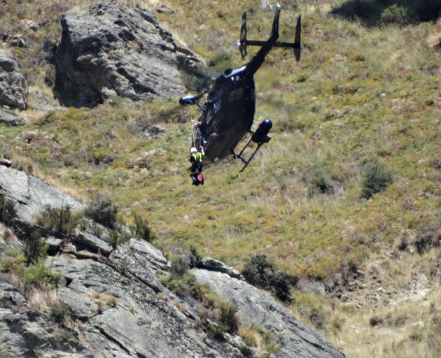 A paramedic is about to be winched from the Otago Regional Rescue helicoper down to the site of a paraglider crash on Roys Peak yesterday. Photo: Kerrie Waterworth