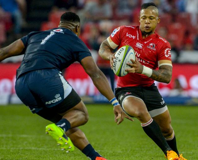 Lions first five-eighth Elton Jantjies is challenged by Bulls prop Lizo Gqoboka during their...