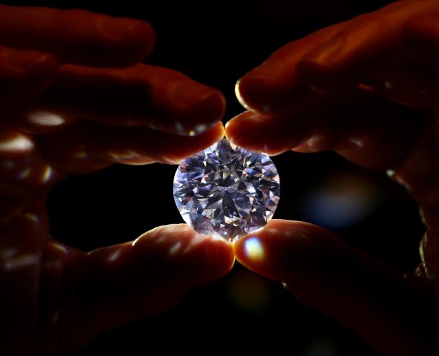 An assistant holds a 102.34 carat white diamond at Sotheby's auction house in London, Britain...