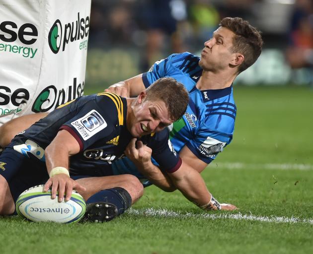 Highlanders second five-eighth Tei Walden, in the tackle of Blues winger Matt Duffie, grounds the ball for a try in their opening Super Rugby match at Forsyth Barr Stadium in Dunedin last night. Photo: Gregor Richardson