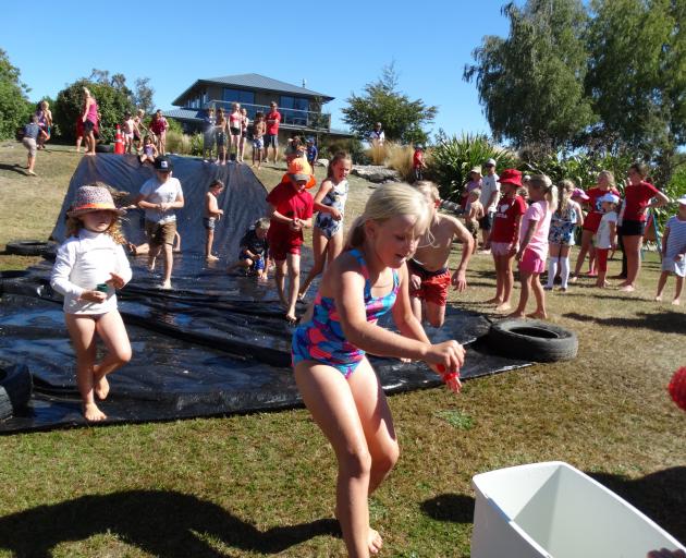 Kerah Alexander (9), of Hawea Flat, adds her eggcup full of water to the bucket after sliding down the waterslide. Country (reds) won with 1.4 litres of water in the bucket compared to the Town team with 1.1 litres of water in the bucket at the end of the