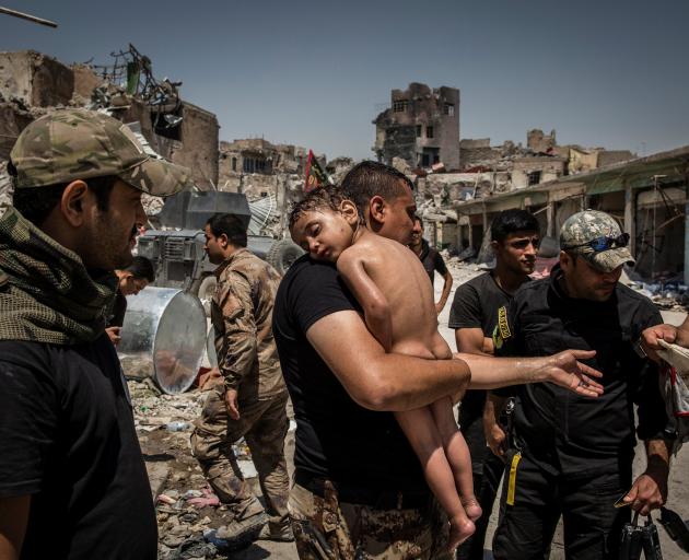 An unidentified young boy, who was carried out of the last IS-controlled area in the Old City of Mosul by a man suspected of being a militant, is cared for by Iraqi Special Forces soldiers last year. Photo: Reuters