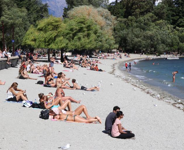 Sunbathers soak up summer heat on Queenstown's lakeside beach. Photo Paul Taylor